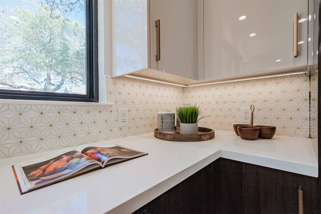 Close up view of the beautifully artistic mosaic tile backsplash and under cabinet lighting.