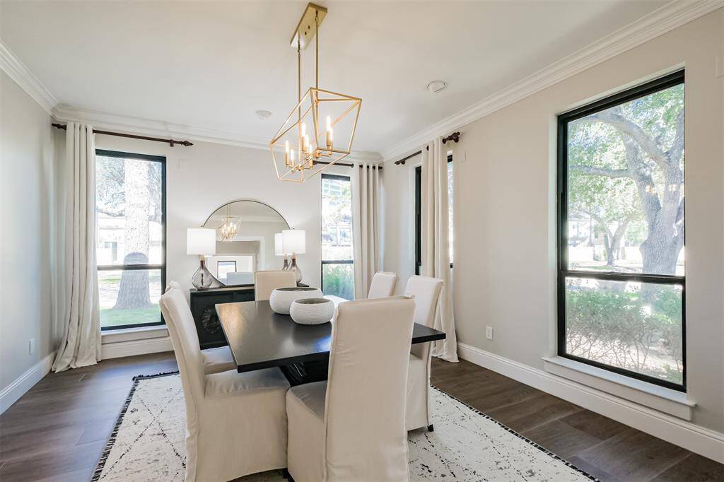 The sophisticated formal dining room features oversized Pella double pane windows, crown molding, gold chandelier, directional lights for showcasing your artwork and window treatments. (previously staged)