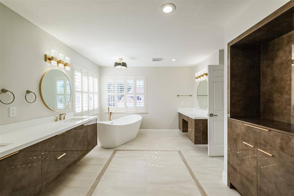 This view of the primary bathroom showcases the large soaking tub, separate vanity area and built-in storage cabinetry. The oversized windows provide an abundance of natural light.