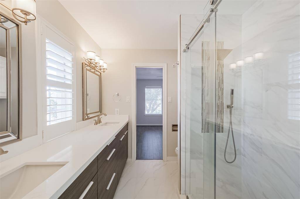 This remodeled Hollywood bathroom features dual Kraus sinks with Grohe energy efficient faucets, quartz counters, sliding glass walk in shower with overhead and handheld shower head and Alvic cabinetry with plenty of storage.