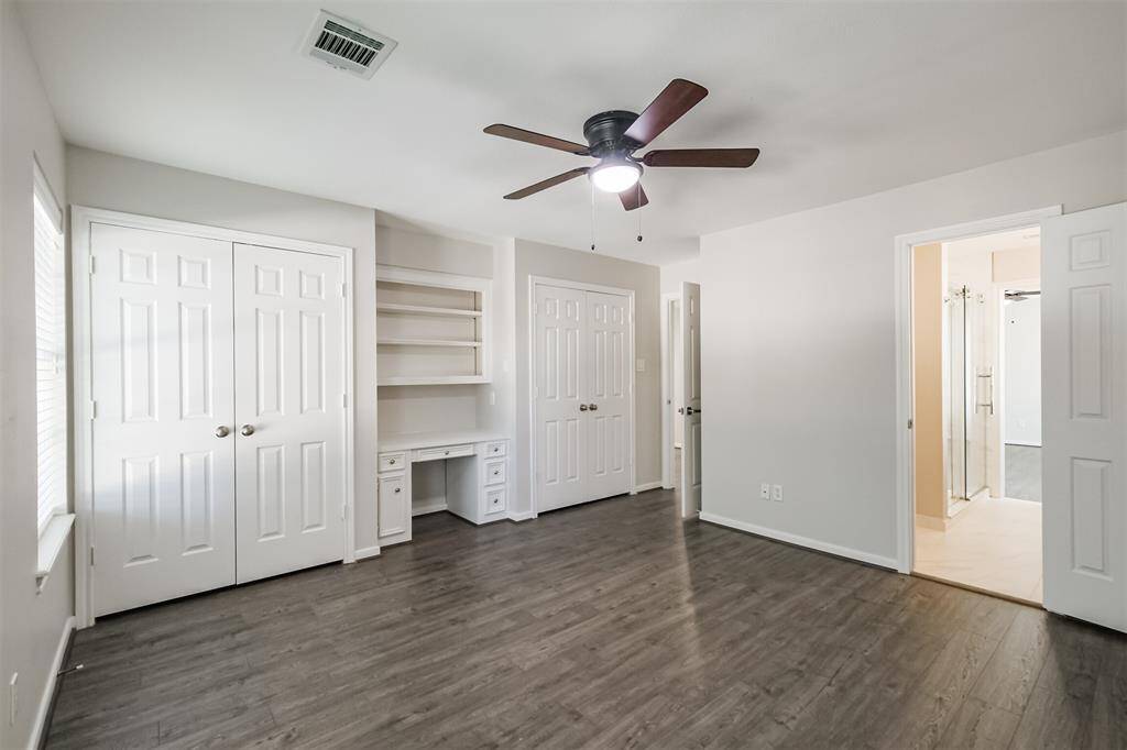 Bedroom 3 features laminate wood flooring, built in desk and shelving, two closets, ceiling fan and access to the Hollywood bathroom.