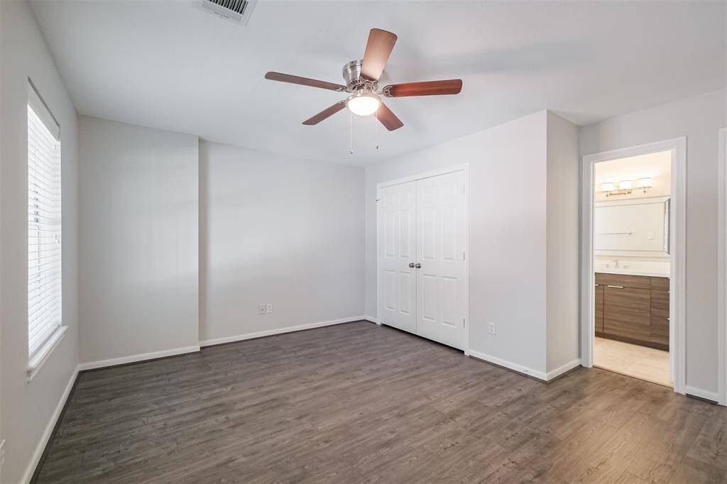 This secondary bedroom features an ensuite bathroom, window treatments, ceiling fan and laminate wood flooring.