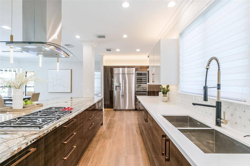 The white quartz counters provide a sleek and neutral backdrop for the custom Alvic scratch and stain resistant cabinetry. The large kitchen island and built in Dacor refrigerator and beverage refrigerator easily accommodate a supplies for a crowd.