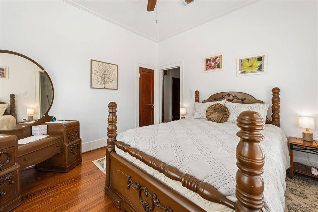 This cozy bedroom features a vintage wooden bed with matching dresser and nightstands. The room has warm hardwood floors, soft lighting, and decorative wall art, creating an inviting and classic atmosphere.