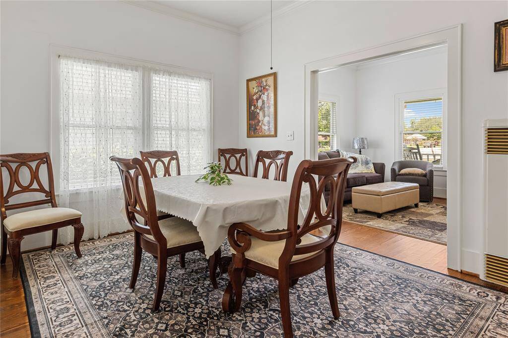 This photo showcases a bright dining room . The space opens to a cozy living area with comfortable seating, large windows, and plenty of natural light.