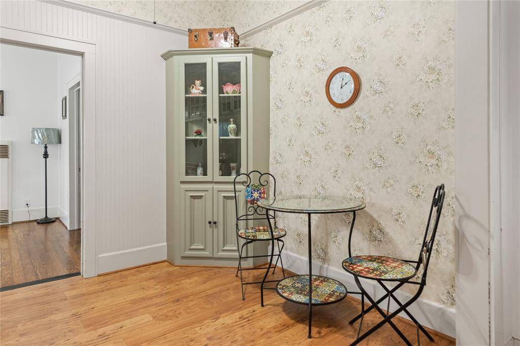 Charming corner in a home features a cozy nook with a glass-top table . A corner cabinet provides storage and display space. Perfect for a small dining area or reading spot.