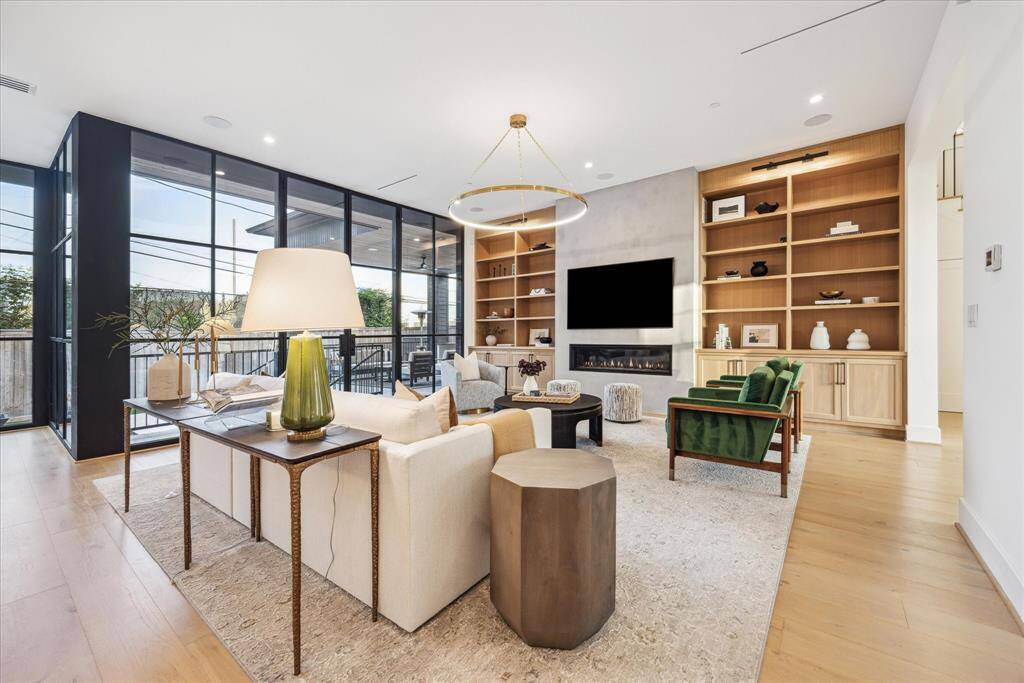 [FAMILY ROOM] The expansive family room is a showstopper—effortlessly blending scale, style, and comfort. Thoughtfully illuminated with designer lighting and built-in display shelves accented by integrated lighting, the space showcases curated décor and refined finishes.