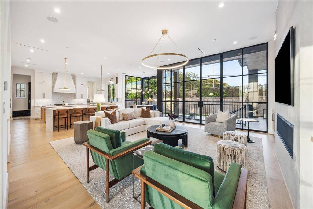 A dramatic wall of oversized windows wraps the room in natural light, creating a seamless connection to the outdoors while enhancing the home’s contemporary elegance.