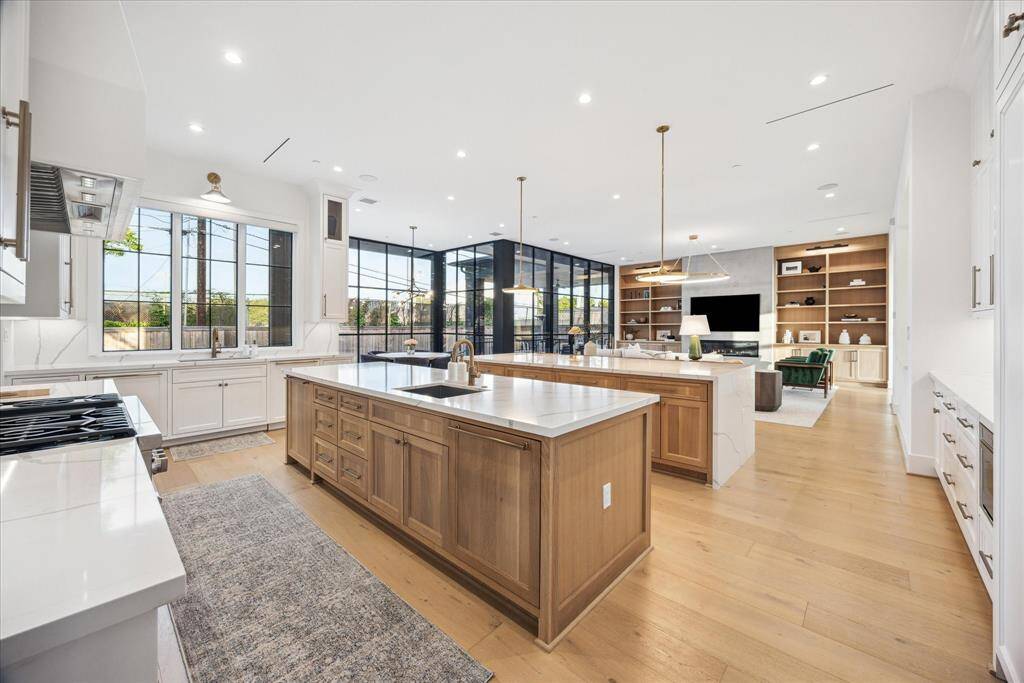 A grand wall of windows floods the kitchen with abundant natural light, creating a bright and airy atmosphere. This entertainer’s dream kitchen seamlessly opens to the spacious family room and adjoining living areas, fostering effortless flow and connection throughout the home.