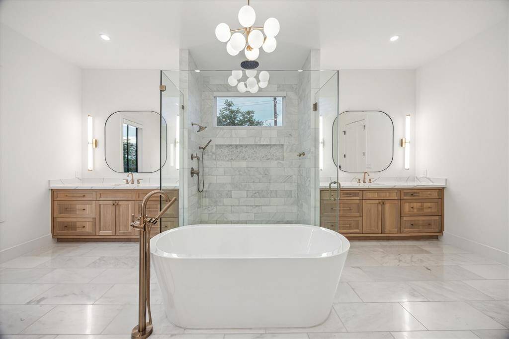 [PRIMARY BATHROOM] Step into the luxurious spa-inspired primary bathroom retreat, where relaxation takes center stage. A graceful free-standing soaking tub and a spacious frameless glass-enclosed shower offer the perfect escape to melt away stress. Two separate, generously sized vanities are adorned with designer lighting and elegant mirrors, providing both functionality and refined style.