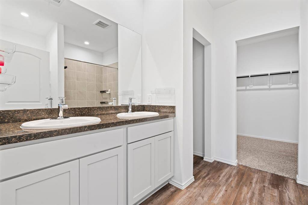 Spacious master bath with dual sinks and walk-in closet access.