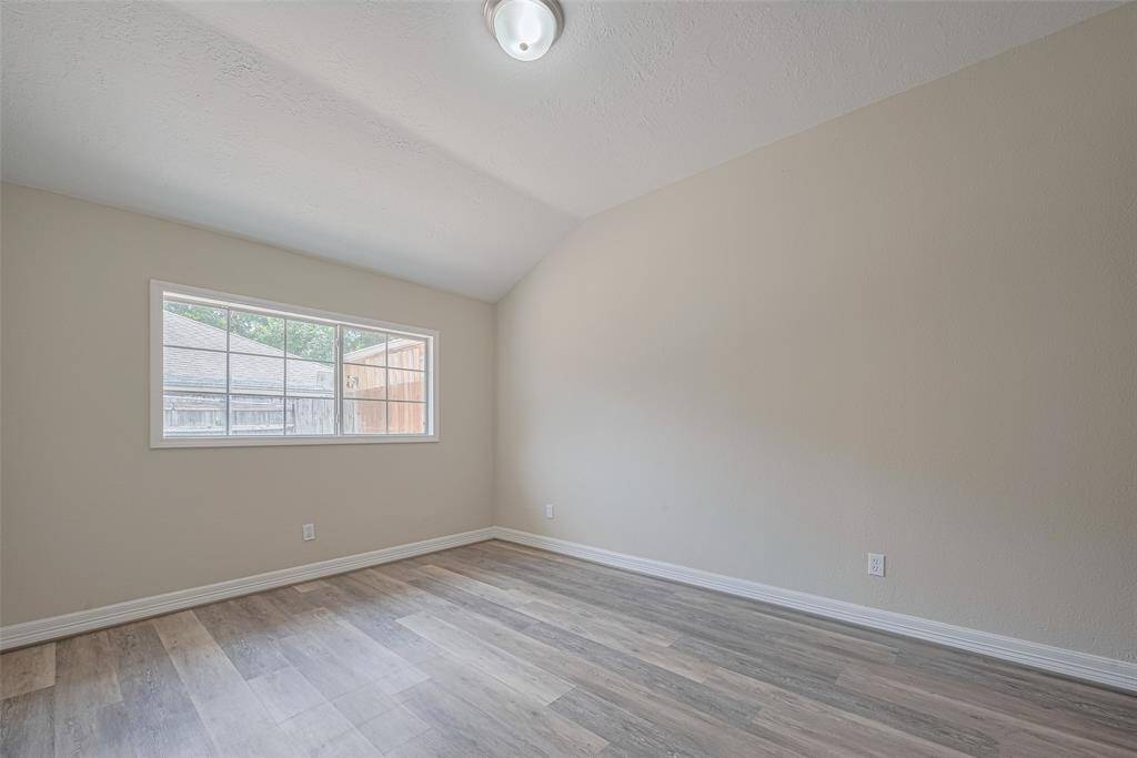 Spacious and subtly vaulted, this primary bedroom is filled with soft light from a wide window.