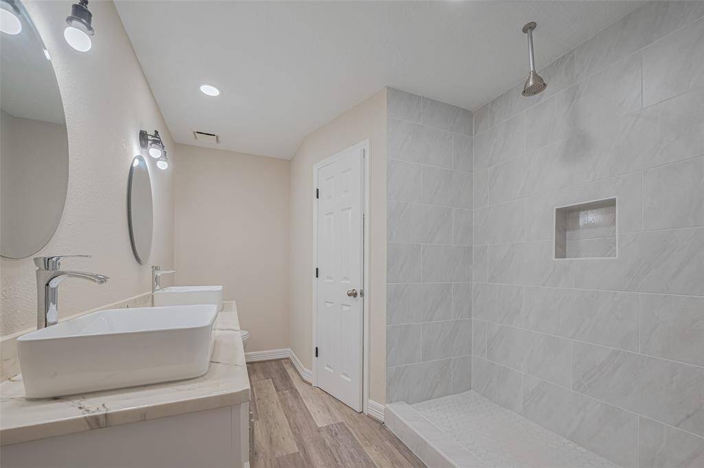 A clean-lined dual-sink vanity and refined shower area are framed in tones of soft sand and stone, offering a space that feels both grounded and elevated in simplicity.
