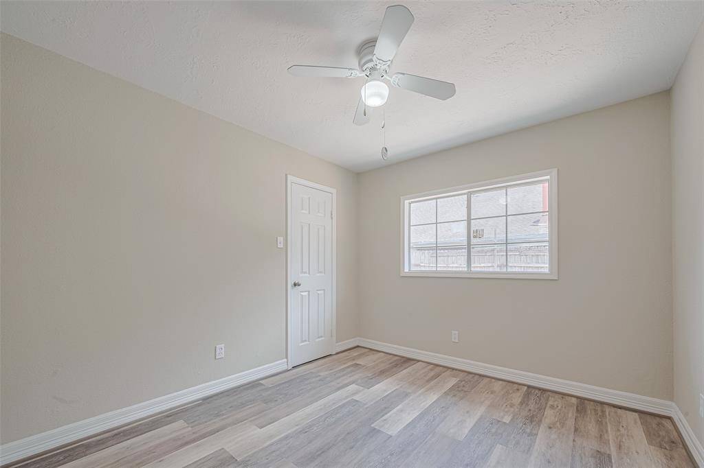 Brightened by a large window and cooled by a ceiling fan, this second bedroom extends the home’s cohesive design language.
