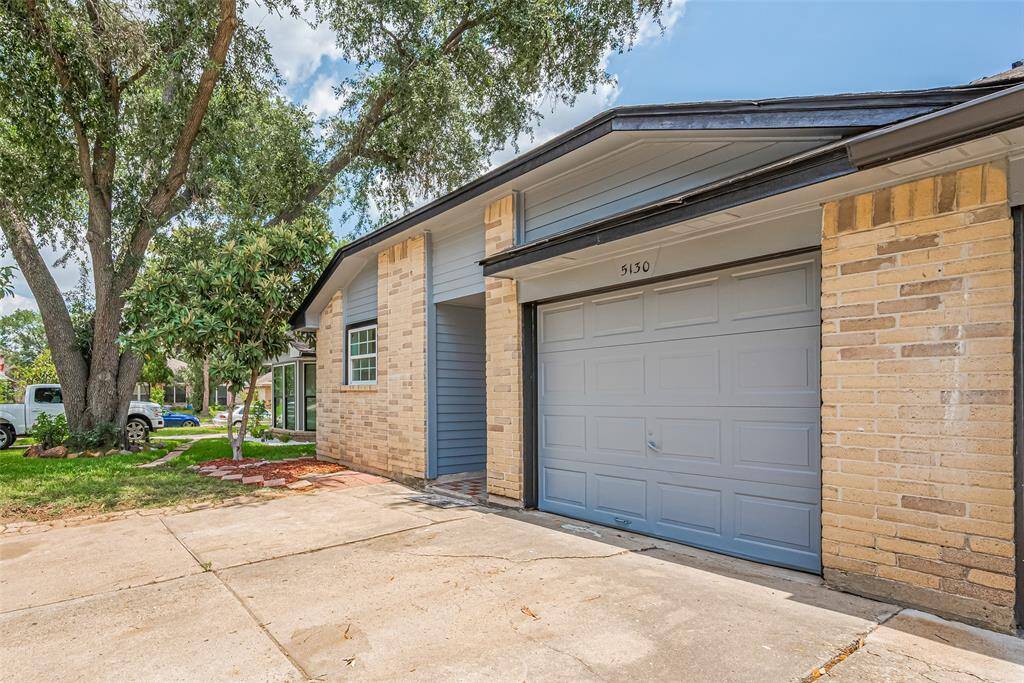 The recessed entryway is subtly tucked beneath the roofline, while the wide driveway provides everyday ease.