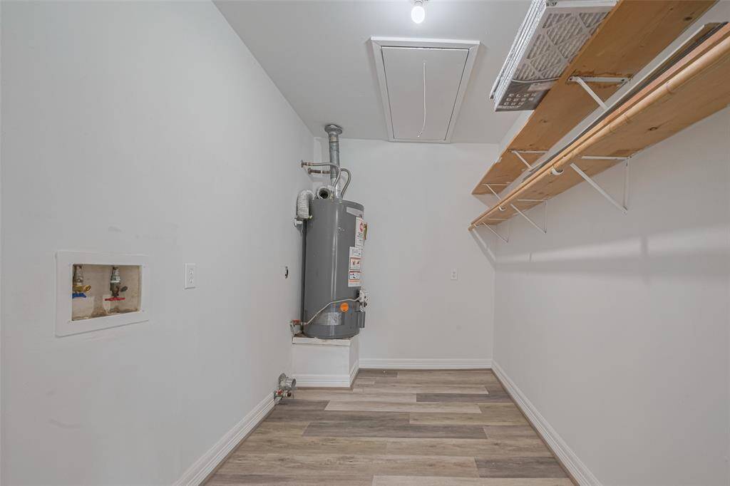 This utility room is smartly designed, with overhead storage that keeps things organized and open floor space that allows for easy laundry routines.