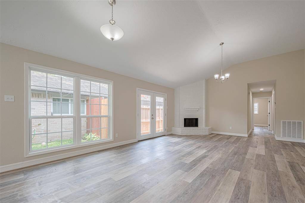 A nearly floor-to-ceiling window washes this generous living space in natural light, drawing attention to the striking white fireplace that anchors the corner.