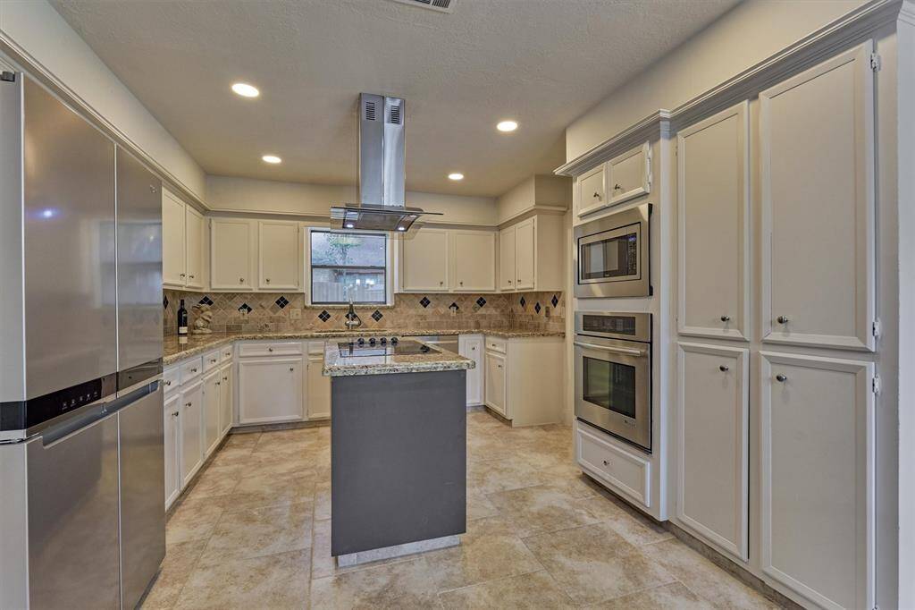 Chef's kitchen showcases central island with electric cooktop, stainless steel appliance, and an abundance of cabinetry.