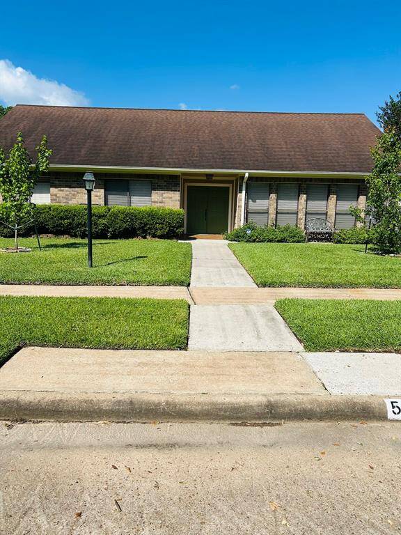 Charming single-story brick home with a large front yard, manicured landscaping, and a spacious driveway leading to a detached two-car garage.