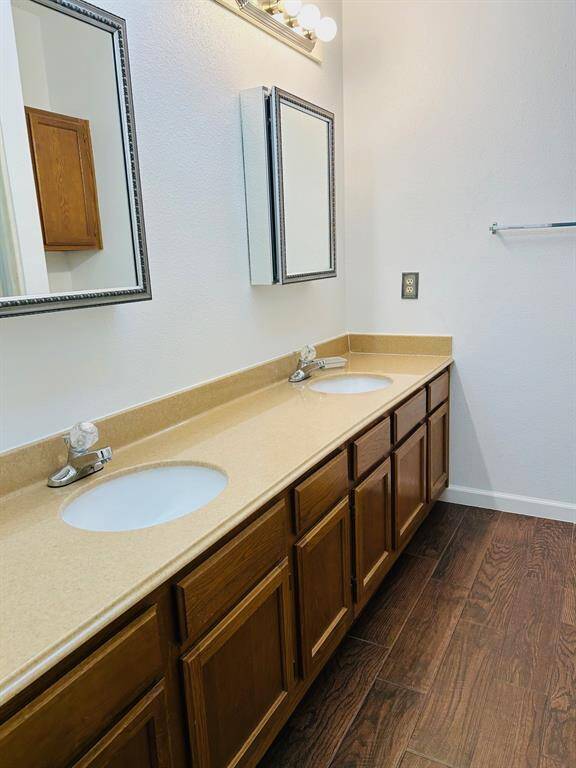 This is a spacious  primary room with wood flooring, light green walls, and a ceiling fan. It features built-in shelving and provides access to a hallway and another room, creating a versatile living area.