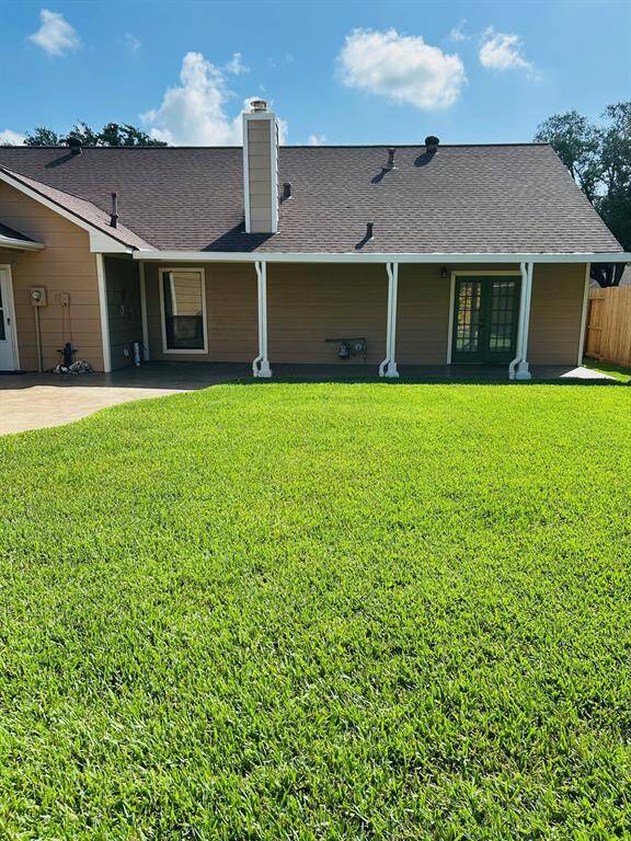 Charming single-story brick home with a large front yard, manicured landscaping, and a spacious driveway leading to a detached two-car garage.