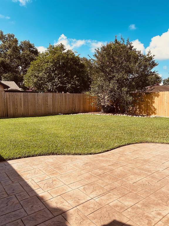 Experience a spacious backyard with a lush lawn, mature trees, and a wooden privacy fence. Perfect for outdoor gatherings, the stone patio invites relaxation under the open sky.