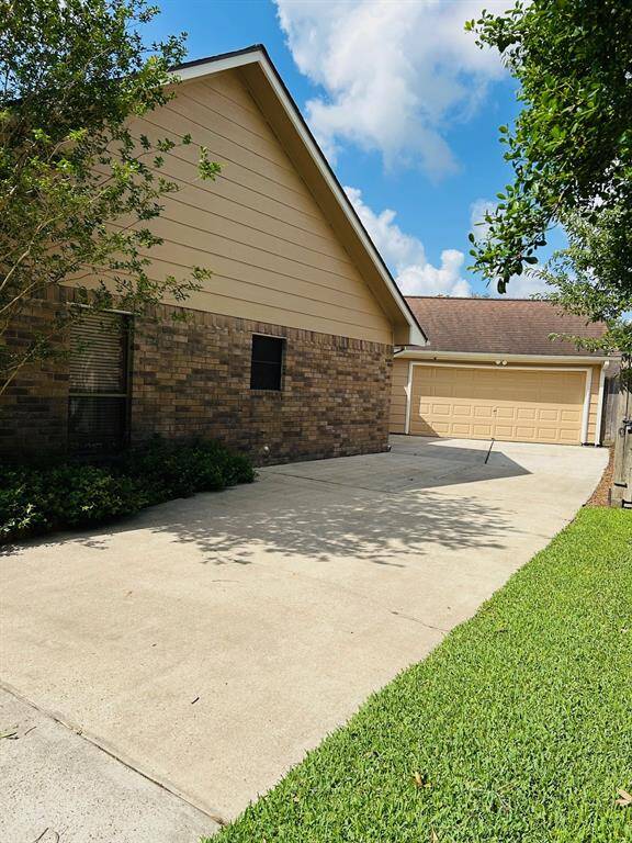 A rare find single-story brick home with a beautifully landscaped front yard and a spacious driveway leading to a detached two-car garage.