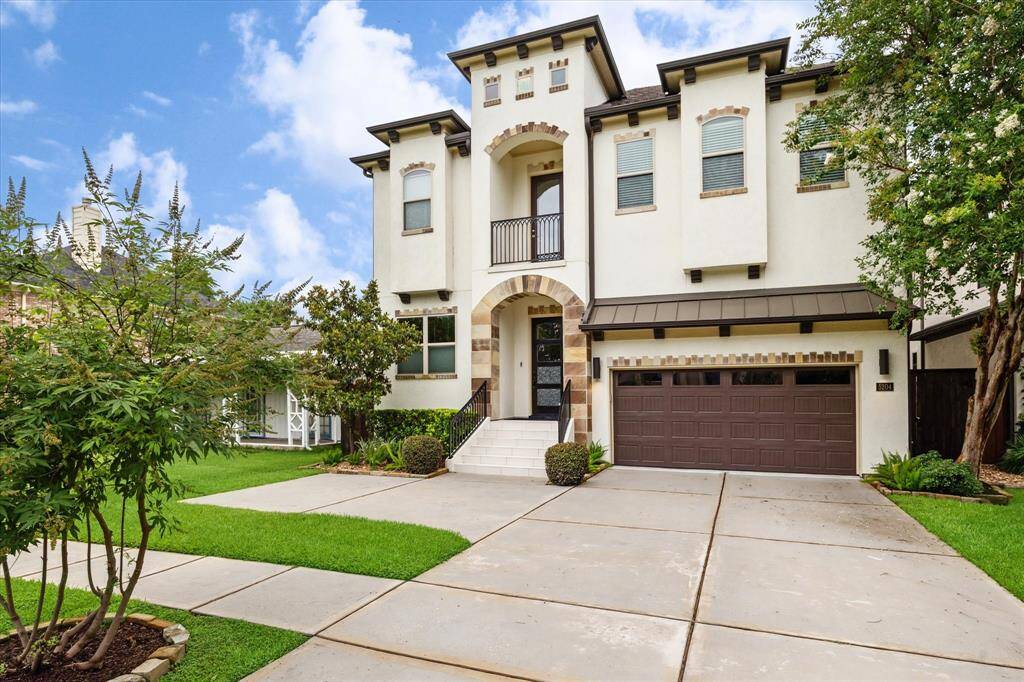 This elegant two-story Bellaire home features a modern façade with arched entryway, large windows, and a balcony. The property includes a spacious driveway leading to a double garage, surrounded by well-maintained landscaping with lush greenery.