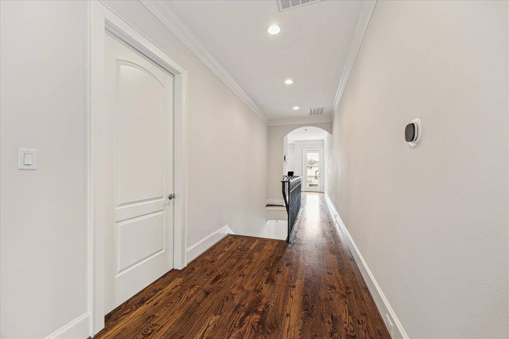 The second-floor landing features hardwood floors and recessed lighting.  The laundry room is through the door to the left.  The game room is towards the end of the hallway.