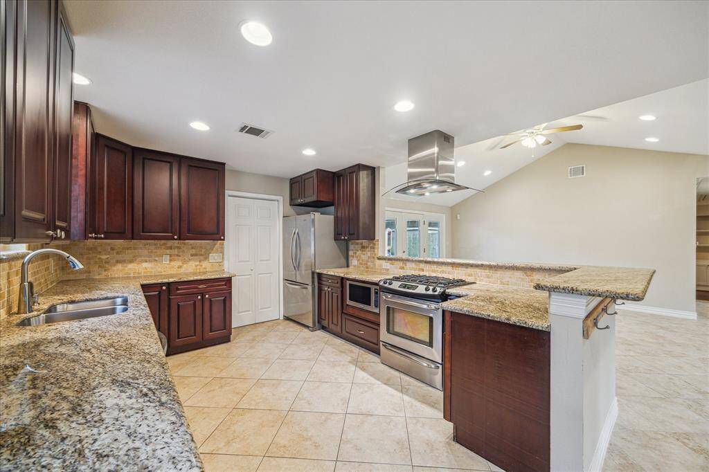 Large Kitchen with Cherry Cabinets, Granite Countertops and Travertine Backsplash. Fridge stays with the home.