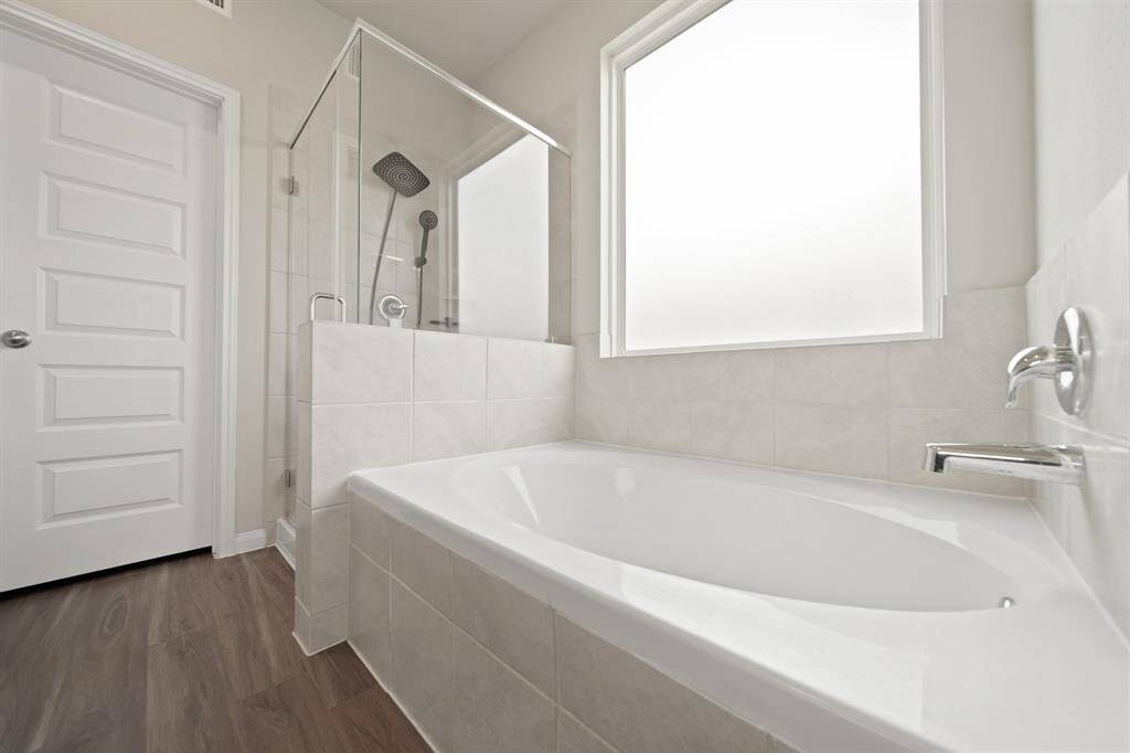 The walk-in closet (not pictured) is through the door near the soaker tub and spacious shower. The large privacy window cascades so much beautiful natural night.