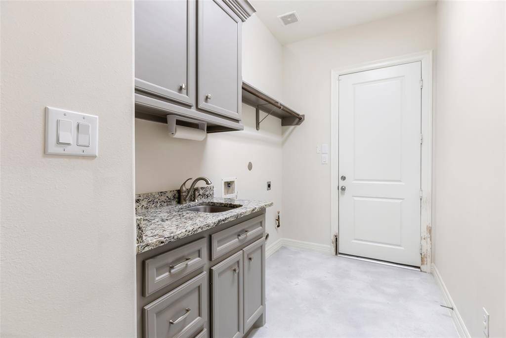 Large laundry room with access to garage, extra storage, and sink