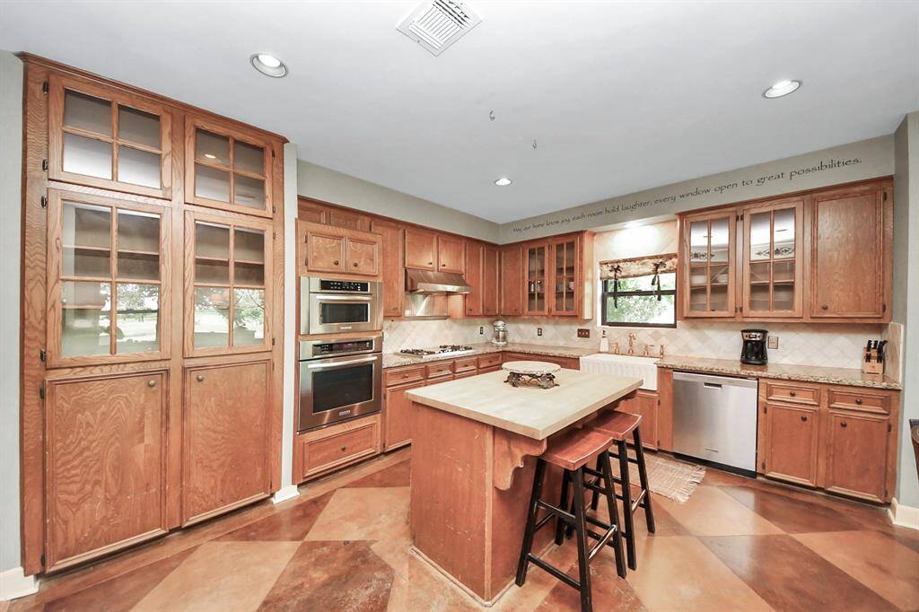 The kitchen features natural wood cabinets, granite countertops, and a large island topped with butcher block—designed to please anyone who loves to cook and entertain.