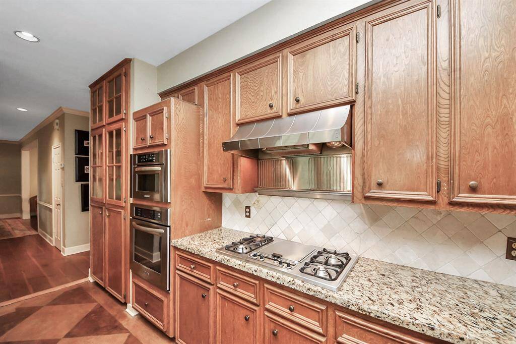 Stainless steel appliances, including a gas cooktop, complement the neutral palette of this kitchen, enhancing its modern yet warm appeal.
