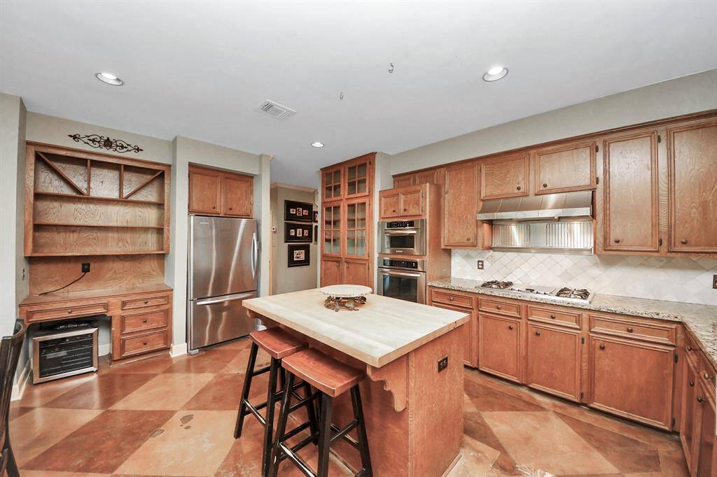 The large island offers room for overflow seating, while a built-in desk provides a convenient spot for bill pay and quick tasks—perfect for busy household needs.