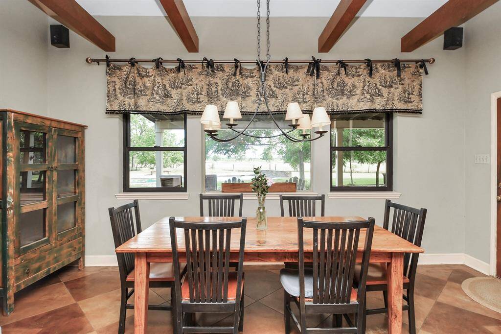 The breakfast room is truly worthy of Architectural Digest, featuring striking wood beams, brand-new windows, and stunning views of the incredible backyard space—making every meal feel special.
