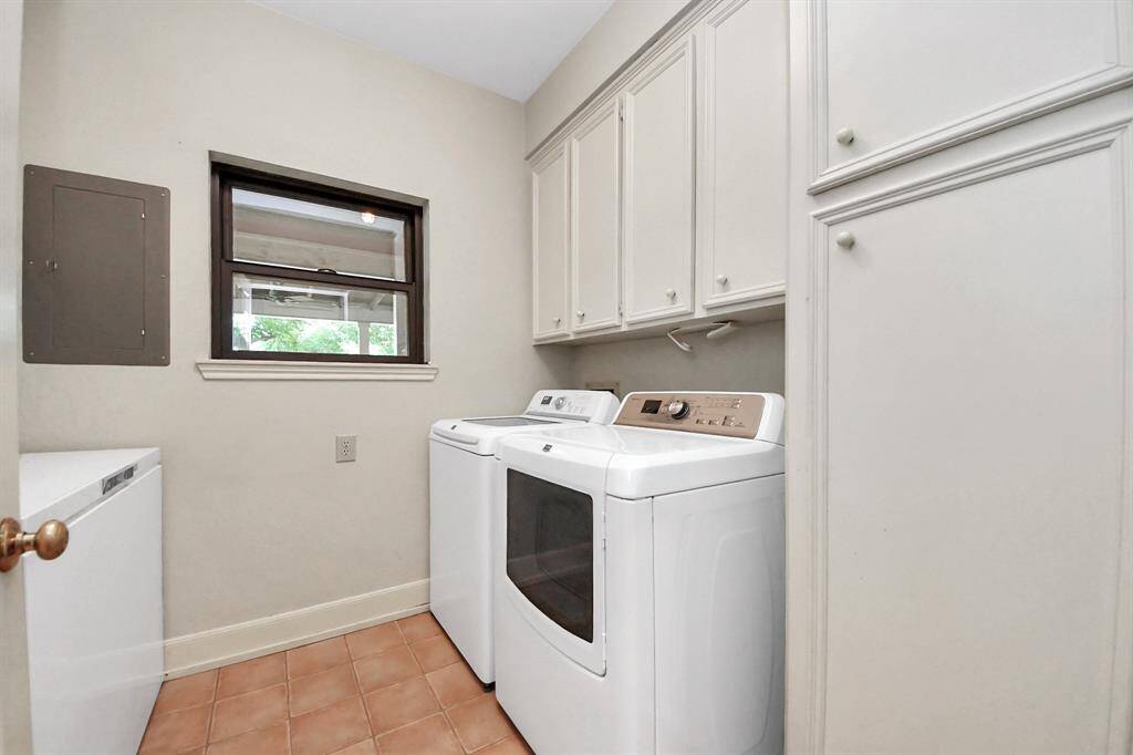 The laundry room offers ample space for a washer, dryer, and extra refrigerator or freezer, complete with a small window that looks out onto the private backyard.