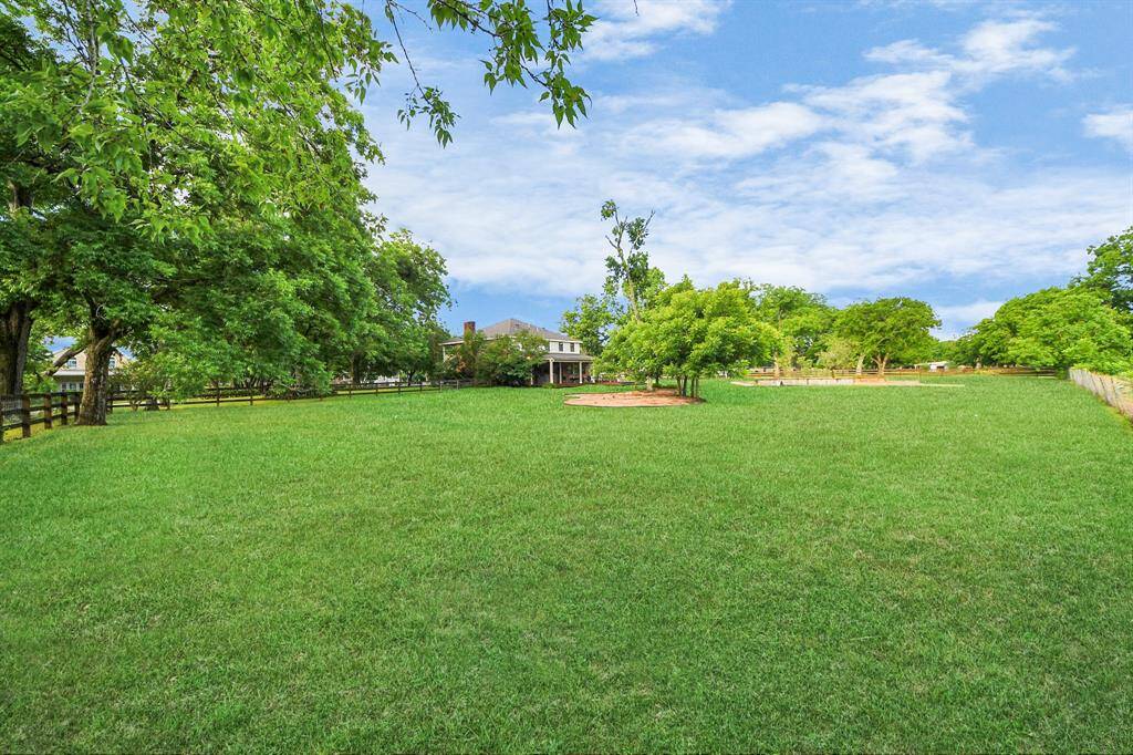A sweeping view of the expansive grounds reveals the pool nestled in the distance, surrounded by open space and mature trees—your country retreat in every direction.