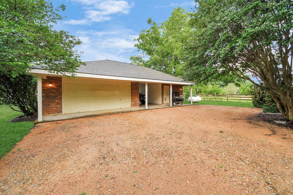This property is highlighted by a two-car garage, a covered carport, and an oversized workshop—ideal for projects, storage, or extra parking.