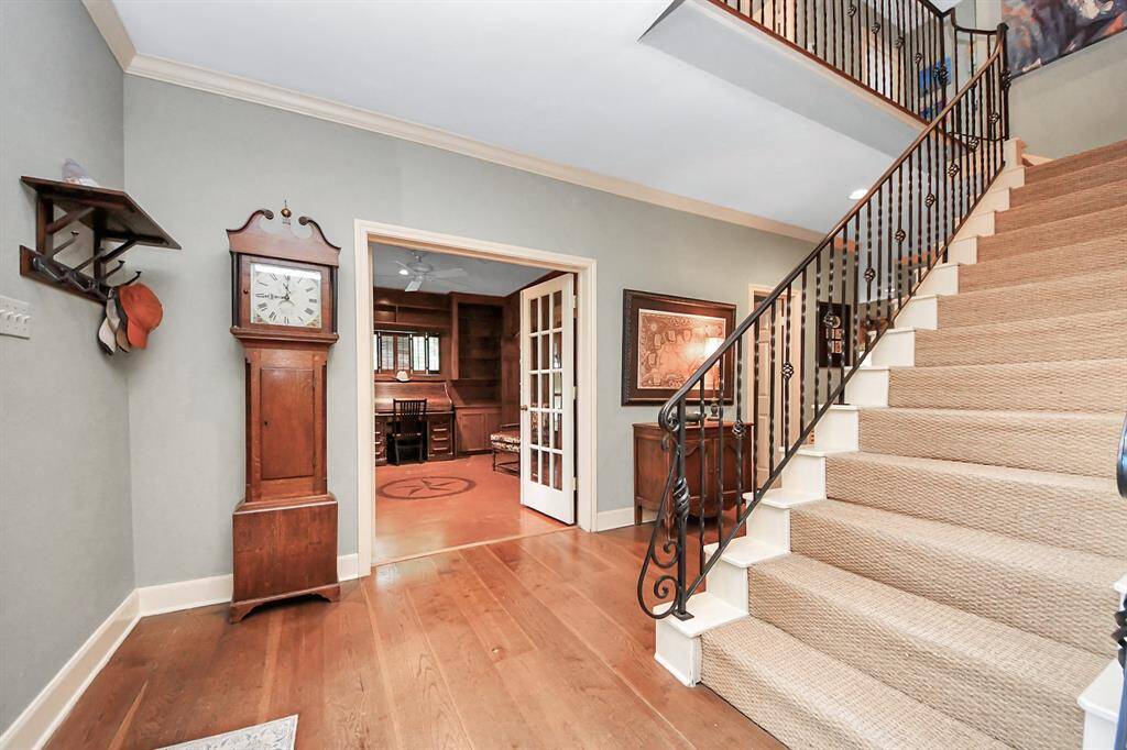 A third view of the entry reveals crown molding, the graceful rise of the staircase, and ample space to accommodate furniture pieces or a classic coat rack.