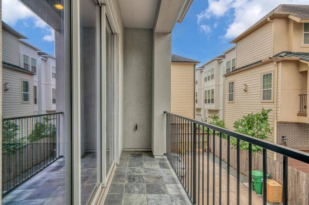 Covered balcony with slate tile flooring and black metal railing offering a cozy outdoor space. It has gas and water connections.