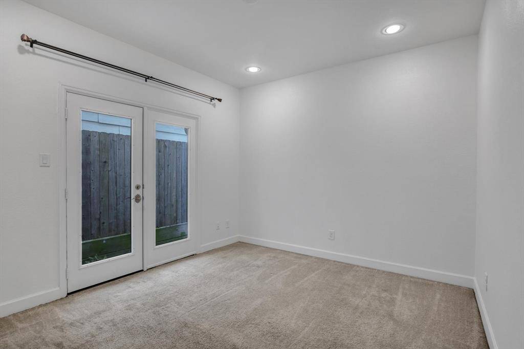 First floor in the right, Spacious bedroom with ensuite bathroom with neutral color carpeting, recessed lighting, and door leading to backyard area, offering a bright and private space.