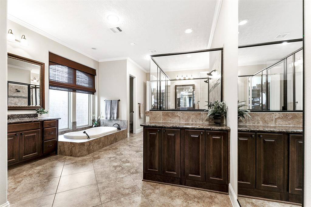 The luxurious primary bathroom features dual vanities, a relaxing soaking tub, a separate glass-enclosed shower, and abundant storage.