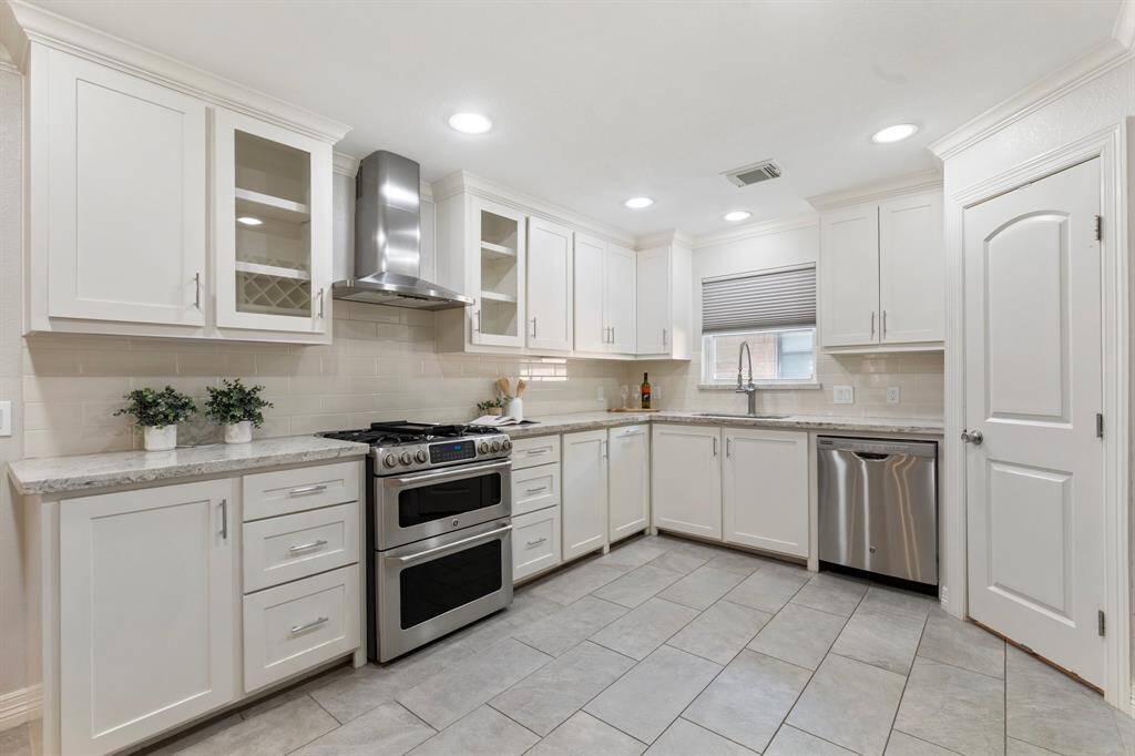 This beautiful kitchen has been decked out with custom cabinets and a gas range with double oven