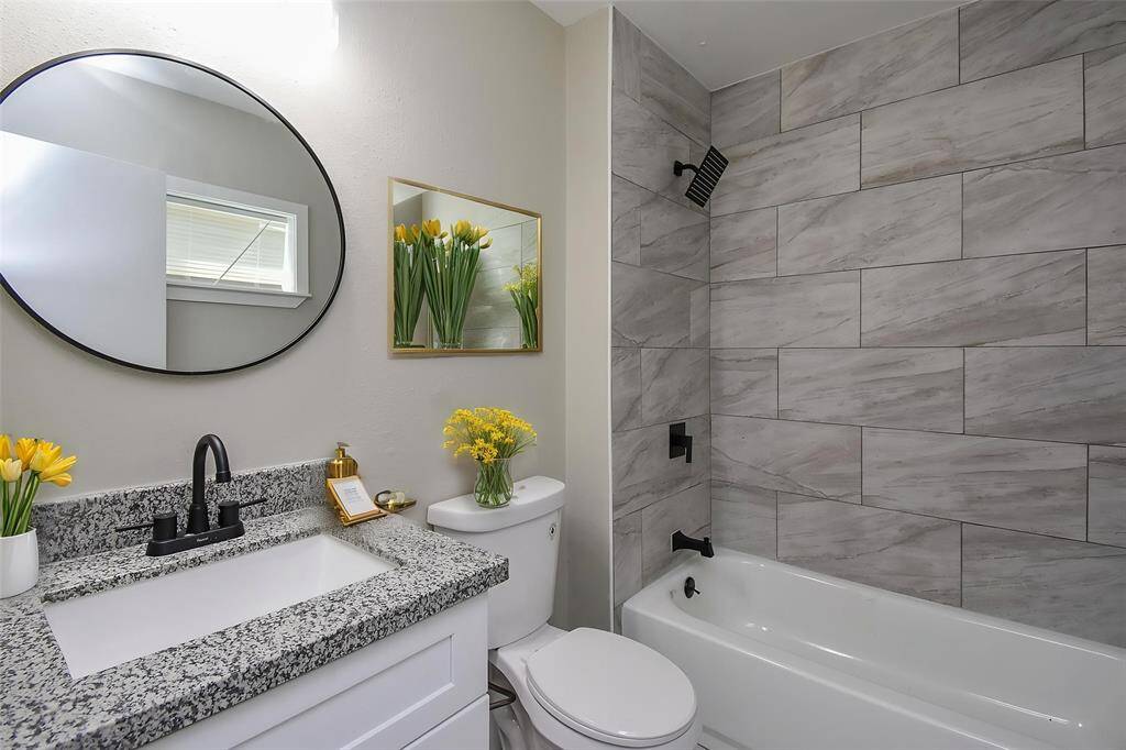 Here is the primary bathroom, with a shower/tub combination with a beautiful tile wall and gorgeous countertops.