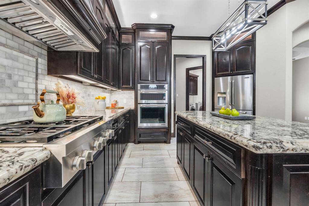 This kitchen features custom cabinets, granite countertops, gas cooktop, and marble subway tile backsplash! 5912 T St., Katy, TX  77493