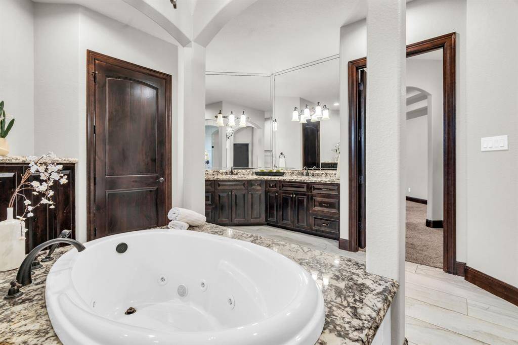 The Ensuite Primary Bath has Granite Countertops, Custom vanity featuring Dual Sinks, an Oversized Jetted Tub, and Tile Flooring! 5912 T St., Katy, TX  77493