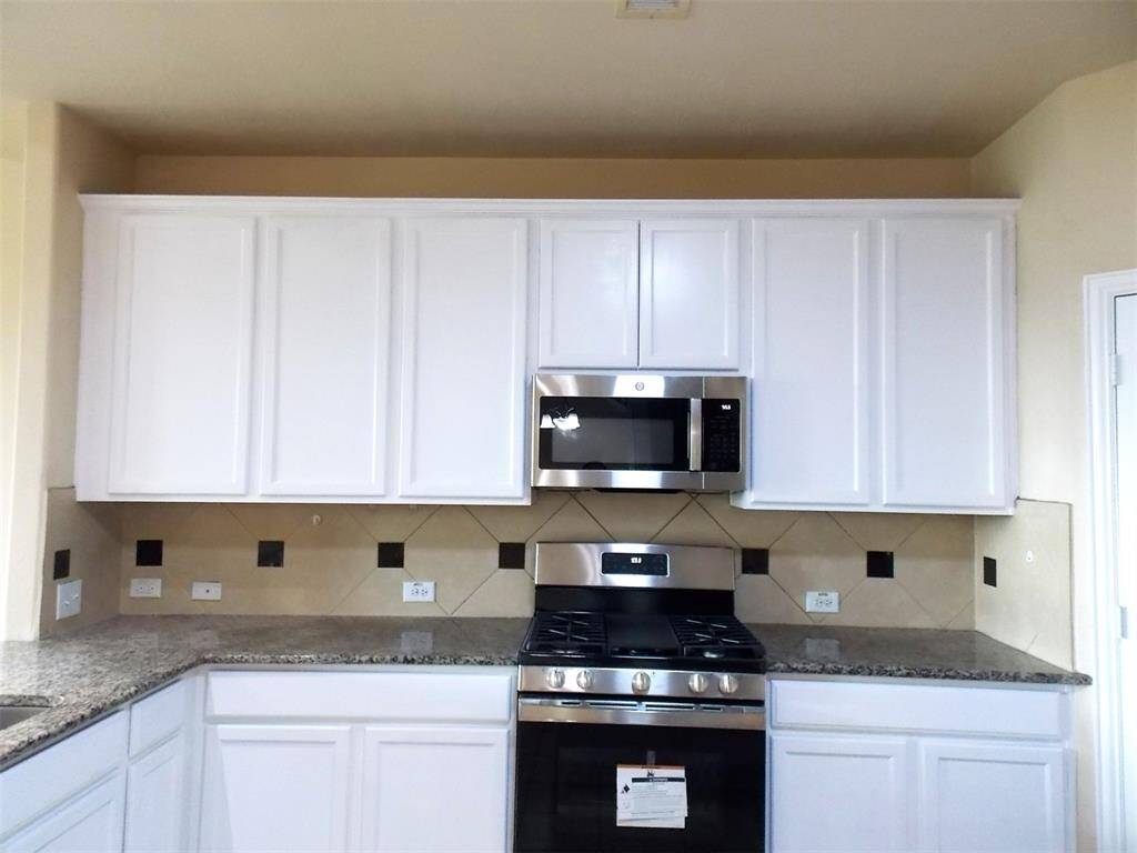 This photo shows a spacious corner pantry with multiple white shelves, perfect for kitchen storage. It has easy access from the kitchen area, with a granite countertop visible nearby.