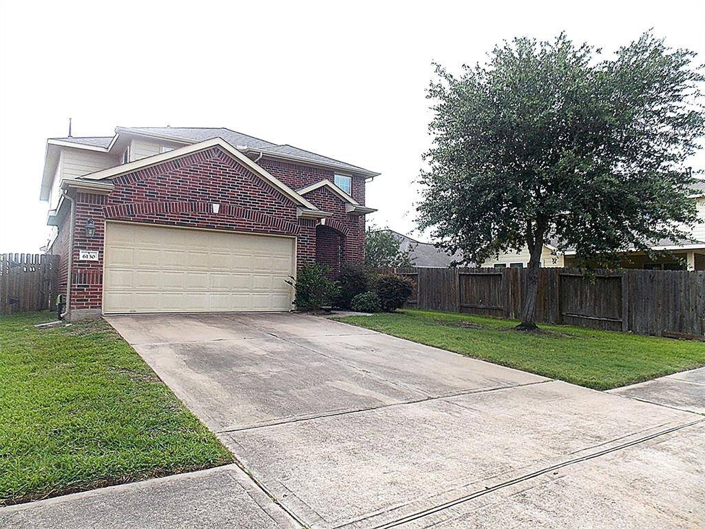 Charming brick home with a two-car garage, nestled in a well-maintained yard with mature trees and a fenced backyard for privacy.