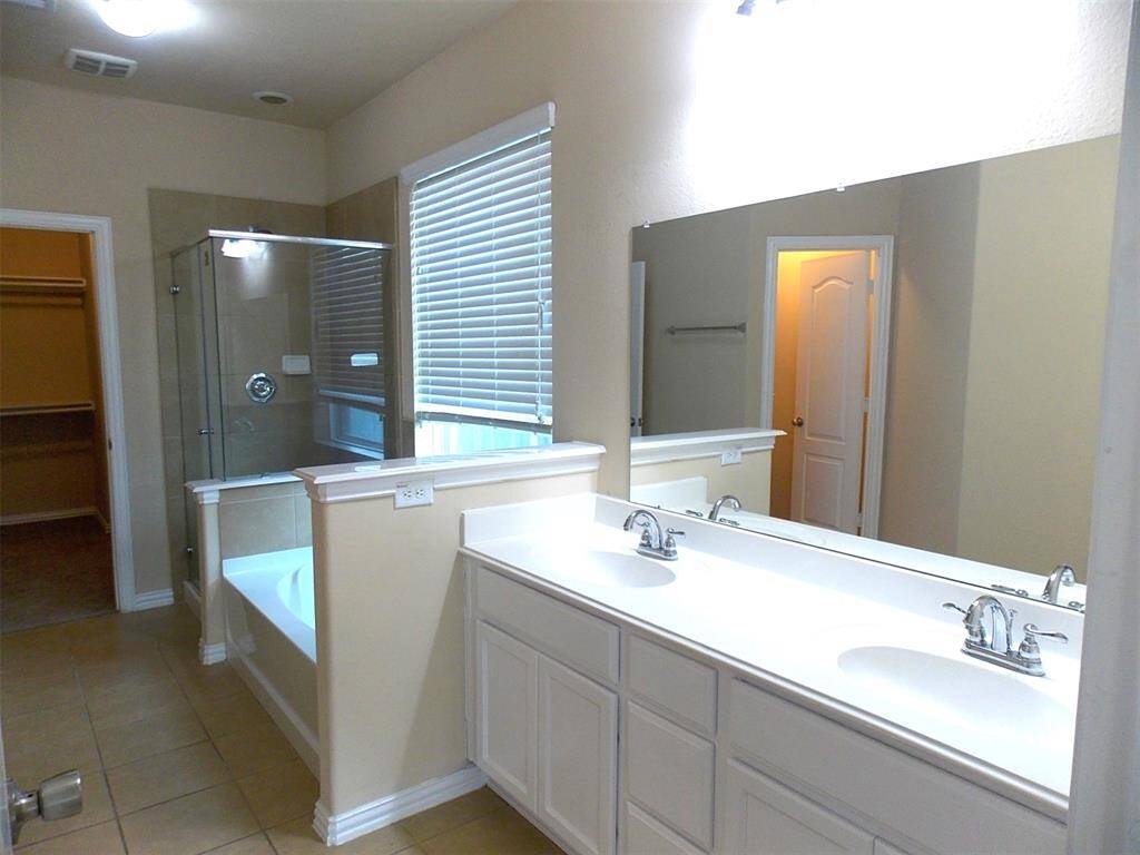 This photo features a well-lit entryway with carpeted stairs leading to an upper level. The space has light-colored walls, tile flooring, and a modern hanging light fixture, creating a welcoming and spacious feel.